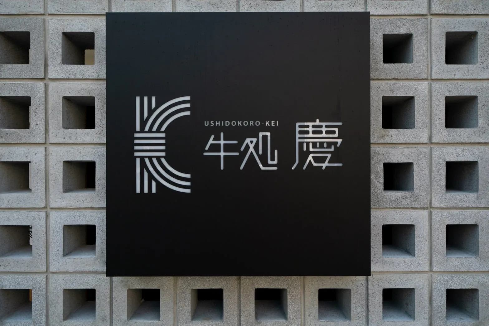 ブロック塀に掛かるロゴの看板