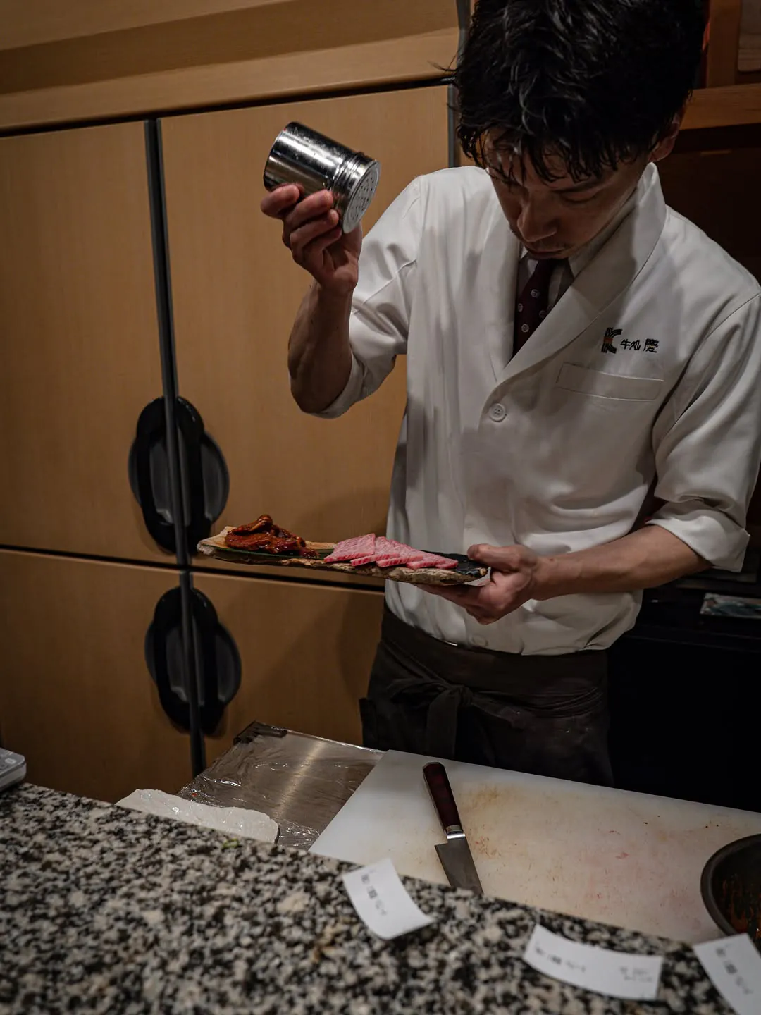 カウンターで肉に塩をふる店長